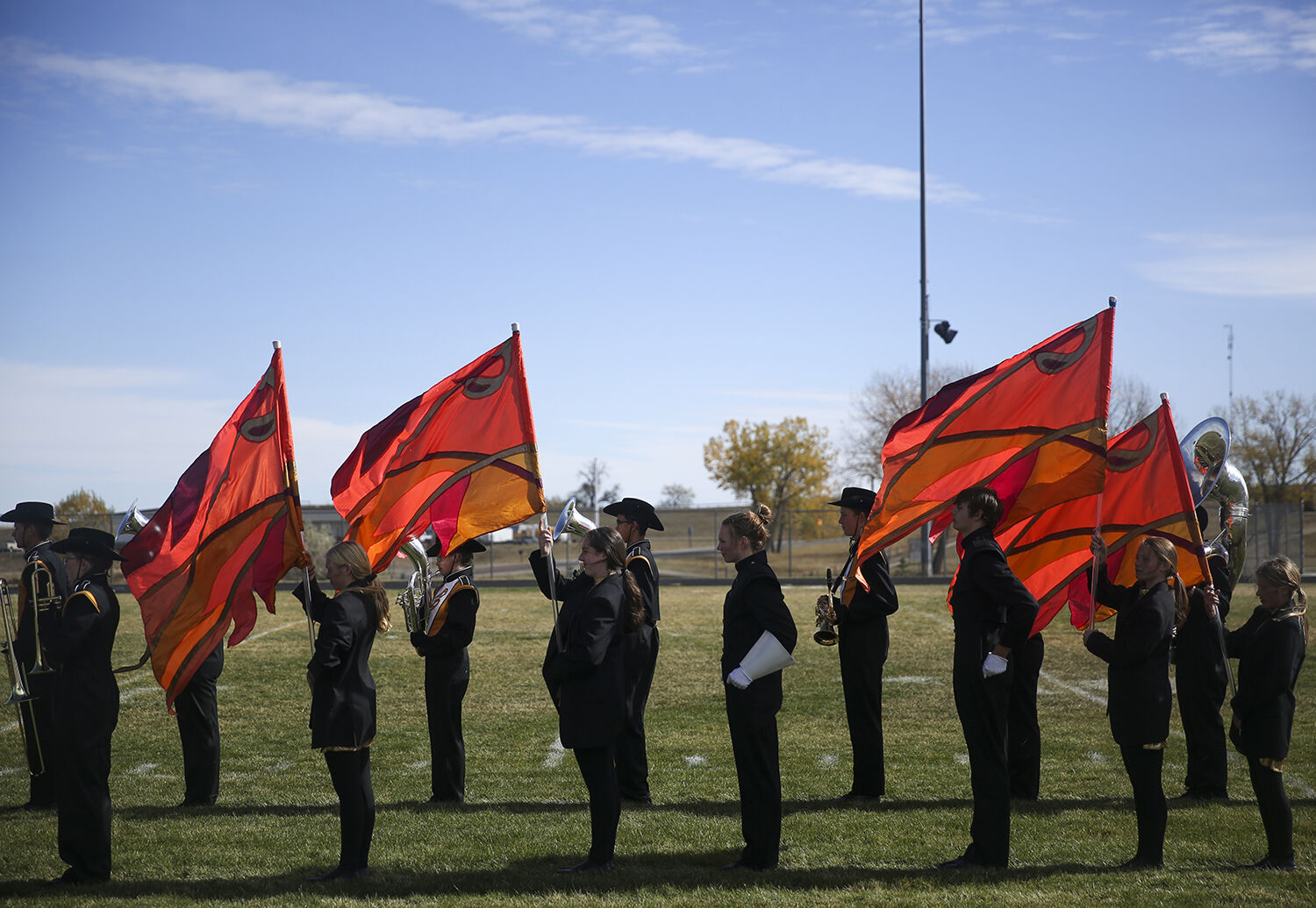Color guard flags flap loosely in the wind as the band stands at attention
